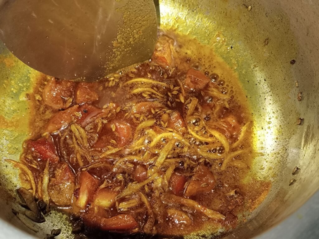 spice base with tomatoes onion and cumin seeds cooking in pot for yellow rice with potato