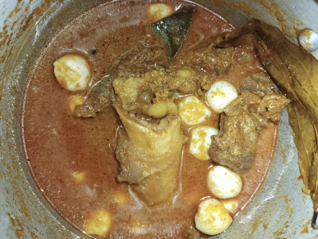 taro pieces and beef pieces cooking together in spiced gravy inside pressure cooker for taro beef stew 