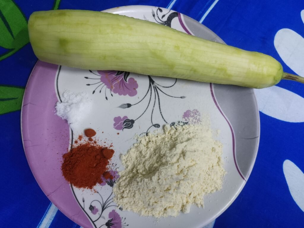  peeled bottle gourd on plate next to gram flour red chilli powder and salt for bottle gourd balls recipe