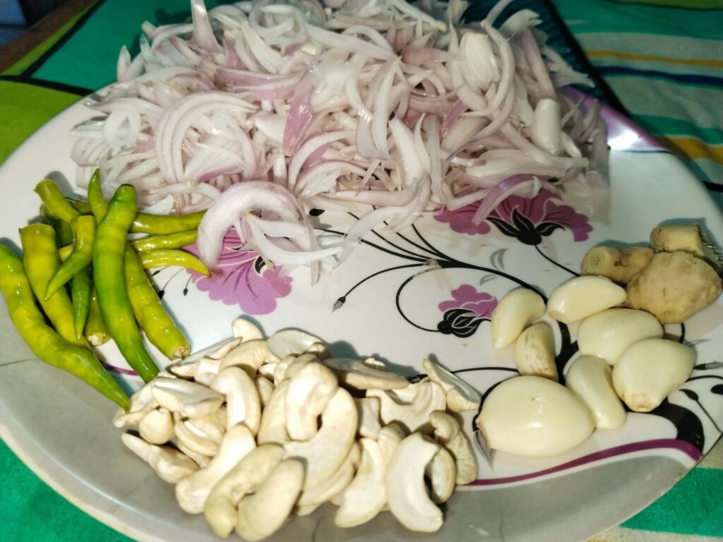 white creamy chicken recipe paste prep plate with sliced onions garlic ginger green chilies and cashews before frying
