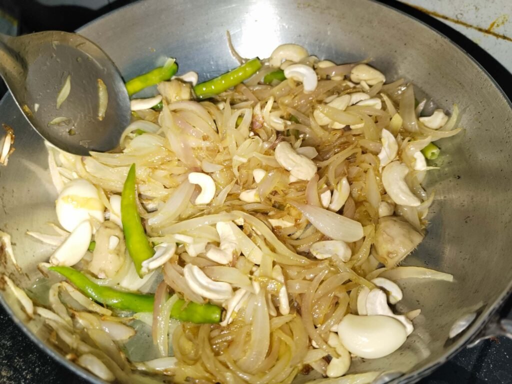 cashews green chilies garlic and ginger added to frying onions in pan for white creamy chicken recipe paste