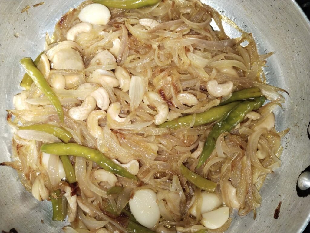 fully golden onion cashew mixture in pan after cooking ready for water before grinding for white creamy chicken recipe