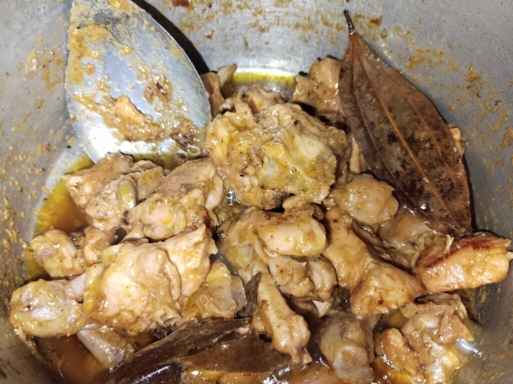 chicken pieces in pot early cooking stage with whole spices visible for white creamy chicken recipe